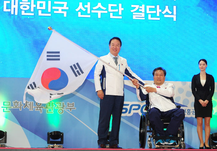 Kim Rak-hwan (second from right), head of the national team for the Incheon Asian Para Games 2014, waves the Taegeukgi, the Korean national flag, after receiving it from Kim Sung-il (left), president of the Korea Paralympic Committee, during the Team Korea launch ceremony for the Incheon Asian Para Games 2014.