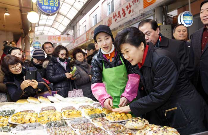 President Park Geun-hye (right) selects a pack of <i>tteok</i> rice cake at Junggok Market in Gwangjin-gu, eastern Seoul, on February 10. 