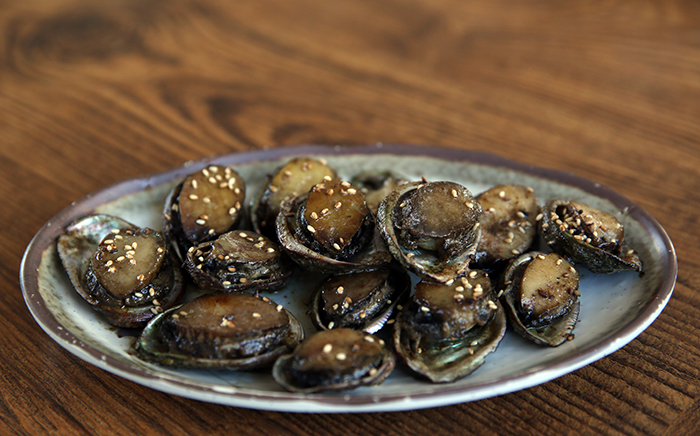
<i>Obunjagi</i>, a type of small abalone, is called <i>tteokjogae</i> in the Jeju dialect. It's popular among foodies thanks to its unique taste. The above photo shows roasted <i>obunjagi</i>.
 