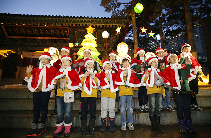 Members of a children’s choir call out, 'Merry Christmas,' and wave to the audience in front of a lit Christmas tree at the main gate to Jogyesa Temple on December 17. 