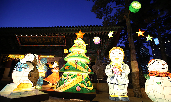 A Christmas tree is switched on in front of the Iljumon, the main gate to Jogyesa Temple, as a symbol of unified religions, on December 17. Next to the tree are large lanterns in different shapes, including a smiling child monk, a snowman and a penguin. 