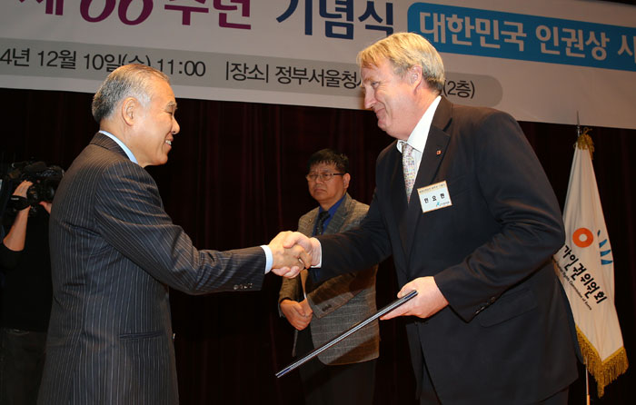John Linton (right) receives the Order of Service Merit of Human Rights Award of the Republic of Korea from Chairperson Hyun Byung-chul of the National Human Rights Commission of Korea on December 10. (photo: Yonhap News)