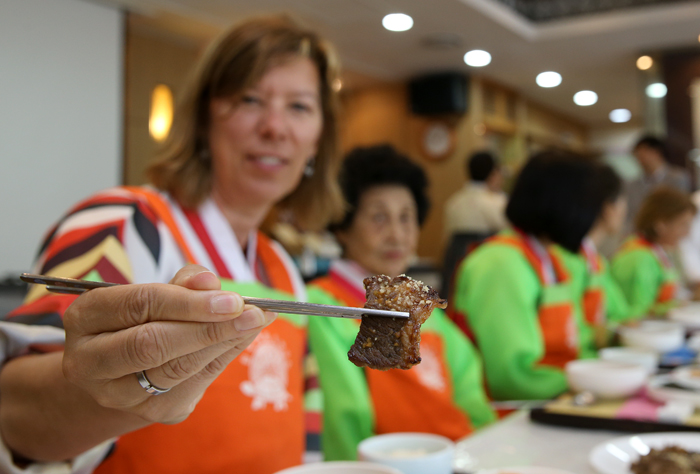 Betty Williams, an American participant uses her chopsticks on a piece of neobiani she made during the cooking class on May 24 (photo: Jeon Han).