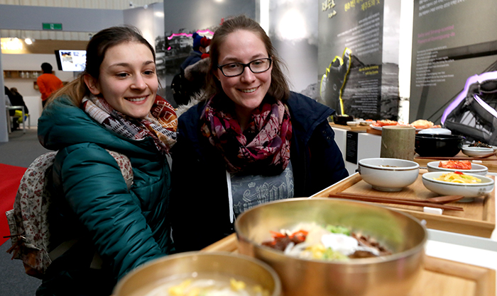 German visitors Isabella Kohlmus (left) and Manuela Bohm stop by the K-food Plaza near the PyeongChang Olympic Plaza for a bite to eat and examine some <i>bibimbap</i> mixed rice, at the Jeollado Province Hall on Feb. 25. (Kim Sunjoo)