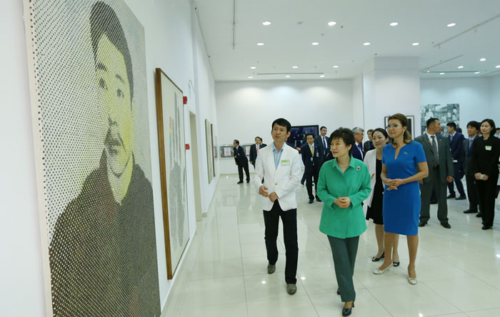 President Park Geun-hye listens to an explanation from the participating artist about the artwork portraying patriotic martyr An Jung-geun (18789-1910) during a cultural exchange exhibition for ethnic Koreans at the Palace of Independence in Astana, Kazakhstan, on June 19.