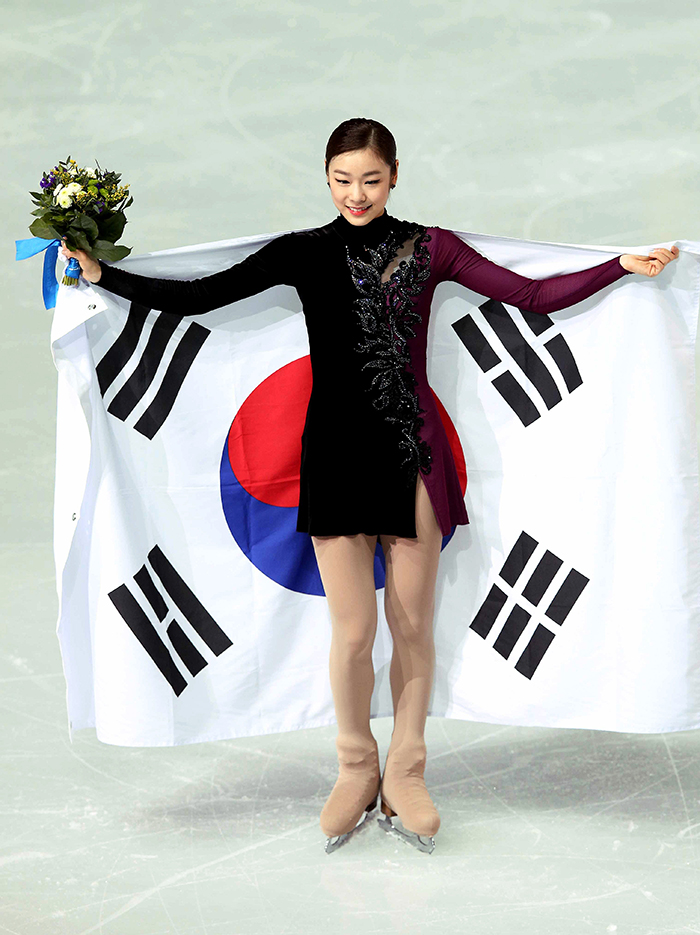Facing the audience, Kim Yuna drapes herself in the Taegukgi, the Korean national flag, after the singles ladies’ figure skating free skating competition at the Sochi Winter Games in Sochi, Russia, on February 20, 2014. (photo courtesy of the Korean Olympic Committee)