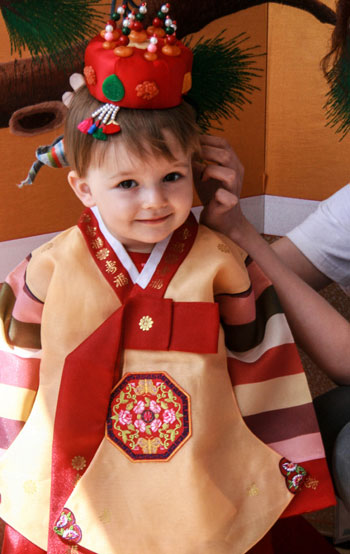 A young child smiles as she tries on a Hanbok, traditional Korean clothing. (photo courtesy of  the Korean Cultural Center Warsaw) 