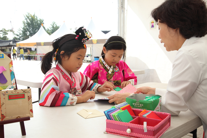 Children wearing Hanbok try origami at the NFMK (photo courtesy of NFMK). 
