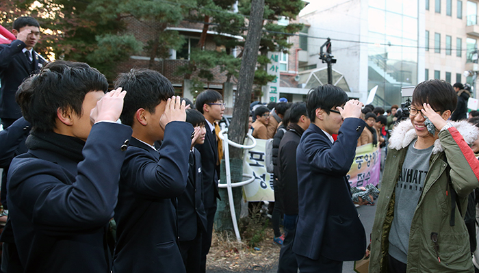 Test-takers from Yongsan High School smile as they enter the test venue to sit their College Scholastic Ability Test (CSAT). Junior schoolmates salute and cheer at the test venue, Kungbok High School, in Jongno-gu (District), Seoul, on November 13.