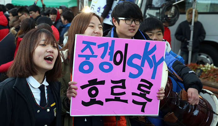 Jungkyung High School students hold up their home-made sign as they cheer on their senior schoolmates who head to the test venue for the CSAT.
