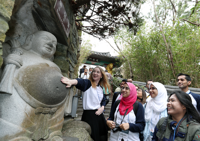 Elena Kubitzki (left), a German honorary reporter, rubs the belly of the Deuknambul (득남불), a statue of Buddha that is said to grant the birth of a son, at Haedong Yonggungsa Temple in Gijang-gun County, Busan, on Oct. 27.
