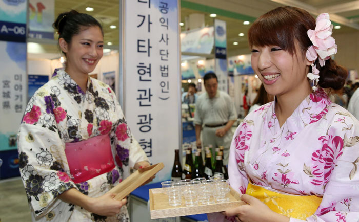 Women clad in traditional Japanese yukatas approach visitors with samples of sake during a sideline event at the Korea-Japan Festival 2014 festival. 