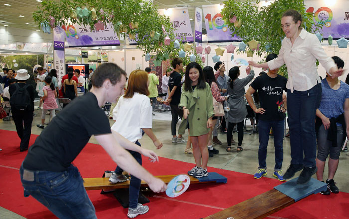 Visitors try the traditional see-saw <i>neolttwigi</i> at the Korea-Japan Festival 2014 in Seoul. 