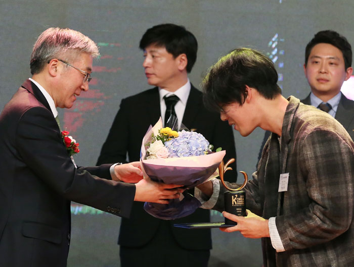 Minister of Culture, Sports and Tourism Kim Jongdeok (left) awards a presidential prize to cartoonist Park Yong-je of ‘God of High School’ at the 2015 Korea Content Awards.