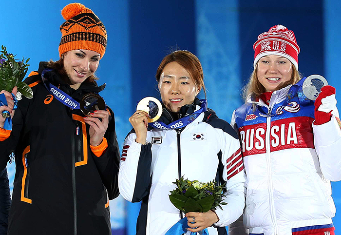 Speed skater Lee Sang-hwa (center) smiles as she raises her gold medal during the award ceremony at the Sochi Medals Plaza, near the Coastal Cluster of Olympic venues, in Sochi on February 12.  From left, Russia's Olga Fatkulina, silver, Lee Sang-hwa, gold, and the Netherlands' Margot Boer, bronze (Photo courtesy of the Korean Olympic Committee)