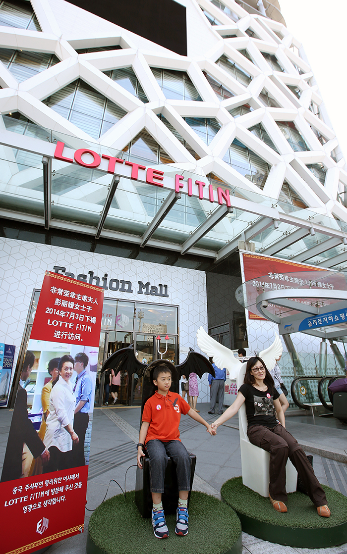Foreign visitors pose for a commemorative photo sitting on the chairs specially set up in remembrance of Chinese First Lady Peng Liyuan’s visit to the shopping mall LOTTE FITIN, in Dongdaemun, central Seoul. (photo: Jeon Han)
