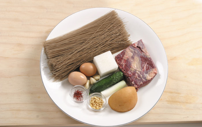 The main ingredients in <i>naengmyeon</i> are buckwheat noodles, beef, eggs, cucumber, green onion, white radish, garlic and pine nuts.