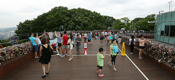 Despite the cloudy weather signaling the approach of the monsoon season, many sightseers and tourists visit N Seoul Tower and take photos of themselves and the 'padlocks of love' on July 22. (photo: Jeon Han) 