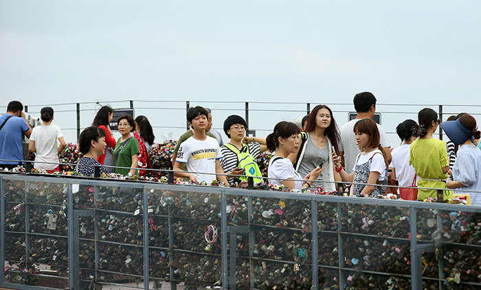 Tourists at N Seoul Tower take photos with the 'padlocks of love' and the heart-shaped chairs. (photo: Jeon Han)
