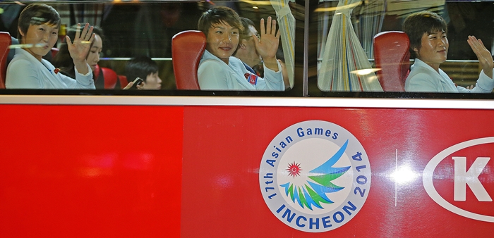 North Korean athletes participating in the Incheon Asian Games wave to the media upon boarding a bus after landing at Incheon International Airport in the late afternoon of September 11.
