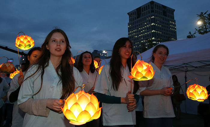 Non-Korean Buddhists and supporters participate in the lighting ceremony as they circle the pagoda-shaped lantern while holding lotus lanterns of their own on April 29.