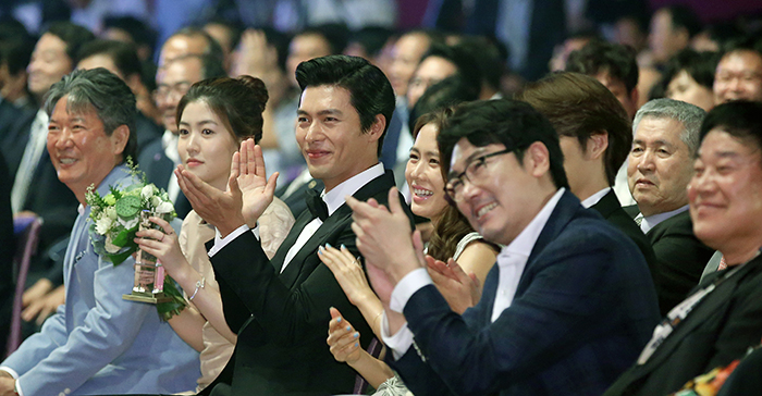 Movie stars, including Shim Eun-Kyuong (second from left), Hyun Bin (third from left) and Son Ye-jin (fourth from left), give a big round of applause during the Pifan opening ceremony hosted by emcees Shin Hyun-joon and Yoo In-na on July 17. (photo: Jeon Han)