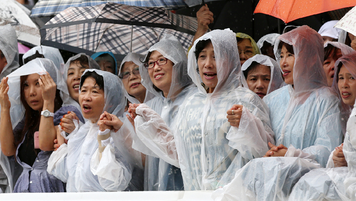  Despite heavy rain, Roman Catholics keep praying outside the Myeongdong Cathedral where Pope Francis celebrates a Mass for peace and reconciliation on August 18. 