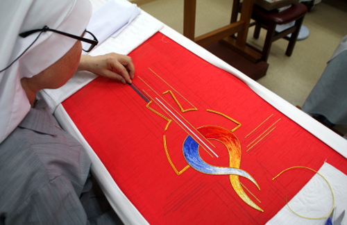 A nun from the Seoul-based Sister Disciples of the Divine Master religious community embroiders a red robe to be worn by Pope Francis on August 16 during his visit to Korea. (photo courtesy of the Preparatory Committee for the Visitation of the Holy Father)