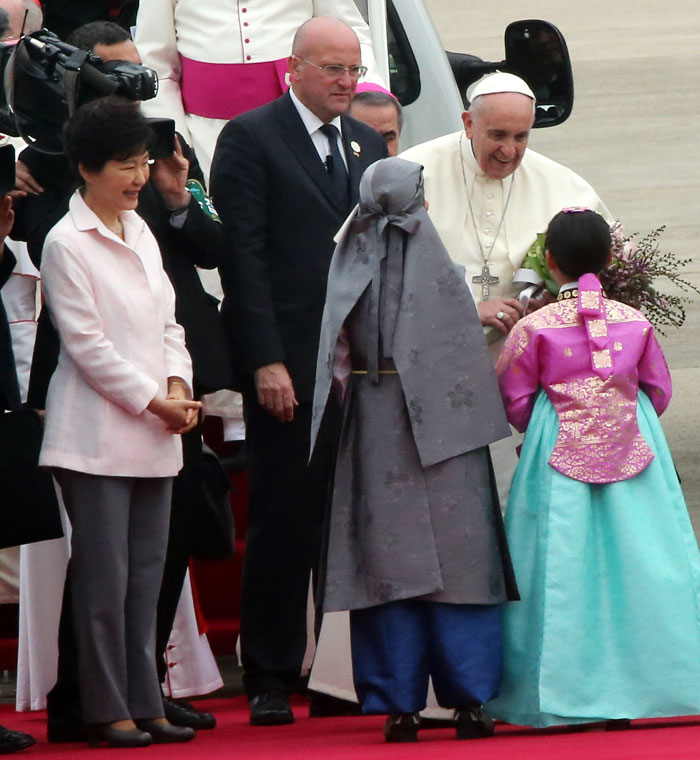 Pope Francis (right), alongside President Park Geun-hye (left), smiles as he receives a wreath from two children on August 14 upon his arrival at the Seoul Airbase. (photo: Ministry of Culture, Sports and Tourism)
