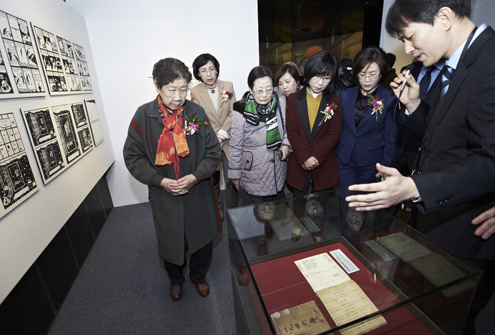 Former “comfort woman” Gang Il-chul (left) and other participants listen to an explanation of some of the historical documents on display. The documents offer evidence of the “comfort women” system that ensnared people to work as sex slaves for Japanese imperial soldiers. (photo courtesy of the National Museum of Korean Contemporary History)