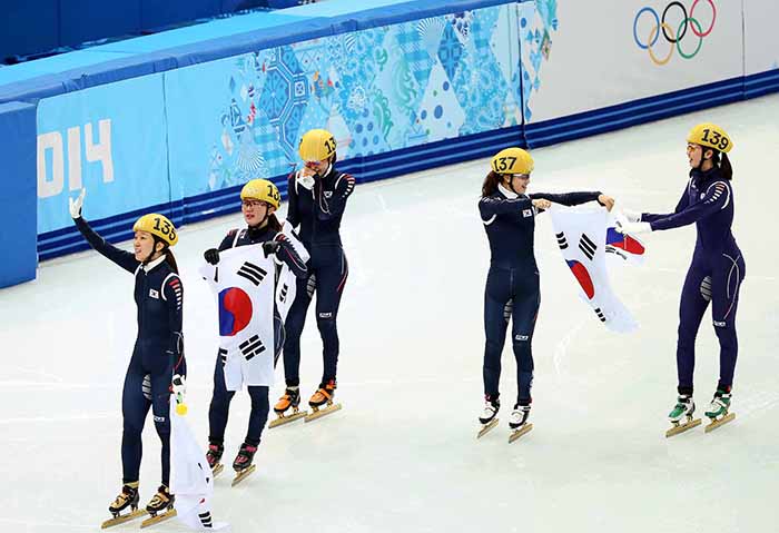 The ladies’ short track team waves to the spectators as it does its celebratory lap around the ice rink holding the Taegeukgi at the Sochi Olympics on February 18. (photo courtesy of the Korean Olympic Committee) 