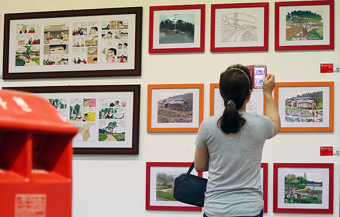 A visitor takes a photo of some of the graphic novel artwork on display at an exhibition during the SICAF 2014 opening ceremony on July 22. (photo: Jeon Han)