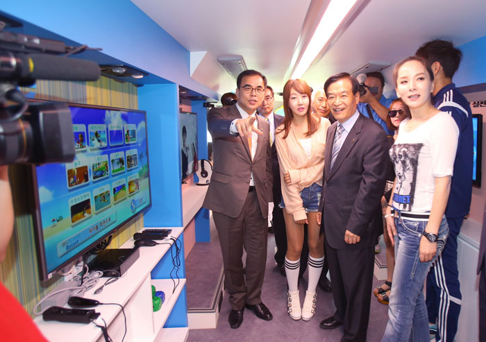 Second Vice Minister of Culture, Sports and Tourism Kim Chong (center) looks around the interior of the Sports Bus with President of the Korea Council of Sports for All Suh Sang-kee, members of the pop group Heart Rabbit Girls and other high-profile sports figures.