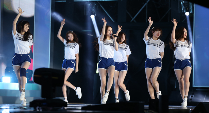 Members of the girl group Gfriend perform while waving to the crowd.