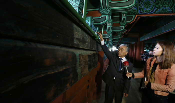 Dancheong master Hong Chang-won explains to a journalist about the coloring of Sungnyemun (photo: Jeon Han). 