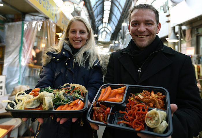 A German couple shows off their lunch trays, stuffed to the brim with delicacies they bought with their yeopjeon tokens at the Dosirak Café on February 20 at Tongin Market. (photo: Jeon Han)