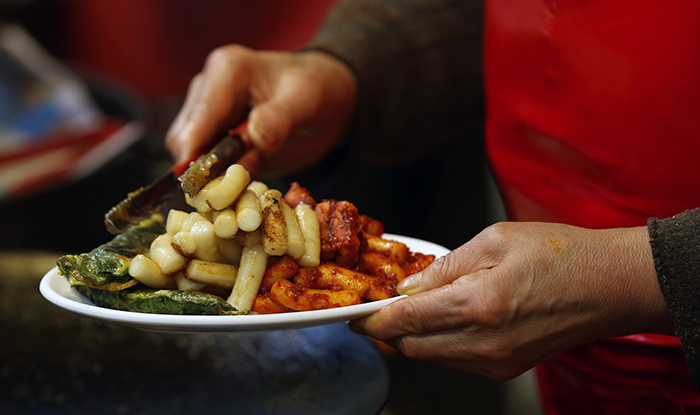 Street vendor Jung Weol-soon says she always serves a full plate of <i>tteokbokki</i>. “Eat a lot,” she says. (photo: Jeon Han) 