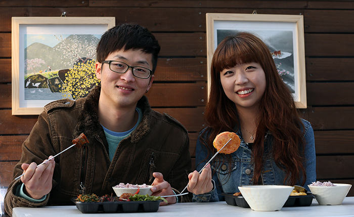 Kim Sun-hyung (left) and Kim Dream, both college students, come from Incheon to eat at the popular do-it-yourself Dosirak Café in Tongin Market on February 20. The pair smiles as they show off their chosen meal. The popularity of do-it-yourself lunches is spreading to other traditional markets across the country. (photo: Jeon Han)