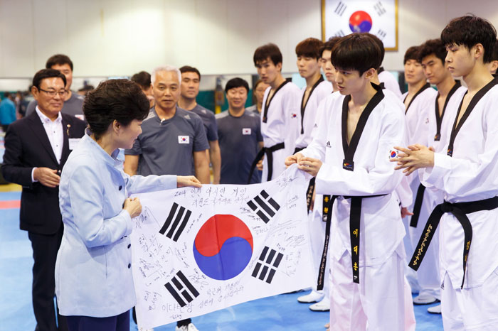 Korean athlete Lee Dae-Hoon gives President Park Geun-hye (left) a Taegeukgi, the Korean national flag, with autographs of the taekwondo athletes during her visit to the Korea National Training Center in Taeneung, Seoul, on August 25. (photo: Cheong Wa Dae)