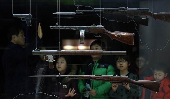 Children at the War Memorial of Korea on January 7 listen to a curator who explains about the weapons used by North Korean soldiers during the Korean War. (Photo: Jeon Han)