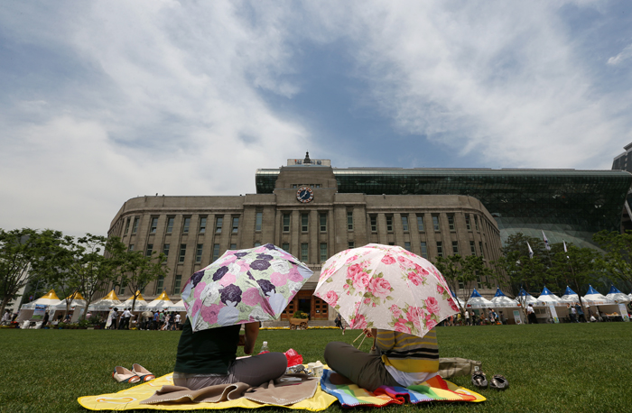 Picnickers enjoy their lunch on the grass of Seoul Plaza in front of Seoul Metropolitan Library and City Hall, downtown Seoul, on May 31 (photo by Jeon Han).