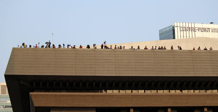 Football fans (top) gather early in the morning in Gwanghwamun Square to cheer for the Korean national football team as it faces off against Russia, on June 18. On the rooftop of the nearby Sejong Center for the Performing Arts (bottom), media cover the crowds watching the Korea-Russia match. (photos: Wi Tack-whan)