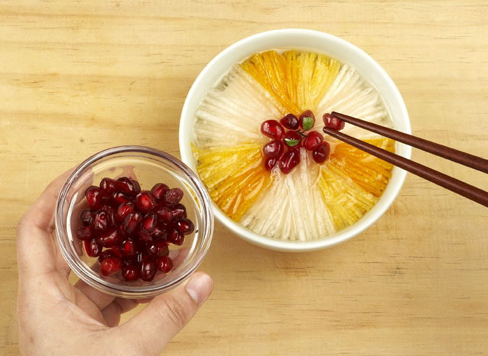 Carefully arrange the pomegranate seeds and pine nuts after putting combining the sliced pears and citron skin with the juice. <i>Yuja hwachae</i> tastes better when the juice is cold.