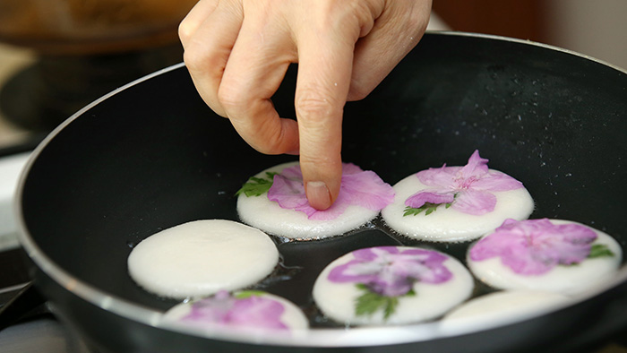 Put the azalea petals on the cooked side. Take extra care to maintain a low heat in order to make the rice cake surface even and flat.
