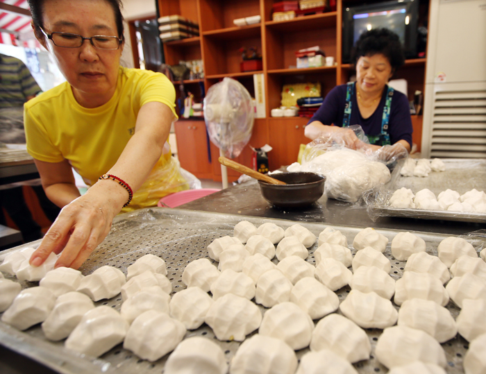  People make half-moon rice cakes with a sweet filling, or <i>songpyeon</i>, with the rice harvested around Chuseok. (photo: Yonhap News) 
