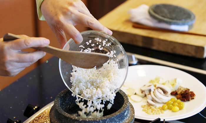Put the non-glutinous rice, glutinous rice, black beans, chestnuts, cultivated pine mushrooms, ginseng and water into a stone pot. Boil it all together over high. When the water begins to overflow, quickly lift the lid to release the steam and then cover it all again.