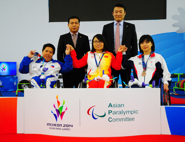  Gold medalist Hu Dandan of China (center) takes a commemorative photo with silver medalist Guion Achelle (left) from the Philippines and bronze medalist Kobayashi Hiromi from Japan. Hu lifted 99 kilograms -- more than twice her body weight -- in the third round of the women's powerlifting 45 kilogram Group A competition and set a new world record, at the Moonlight Festival Garden Powerlifting Venue on October 19. 