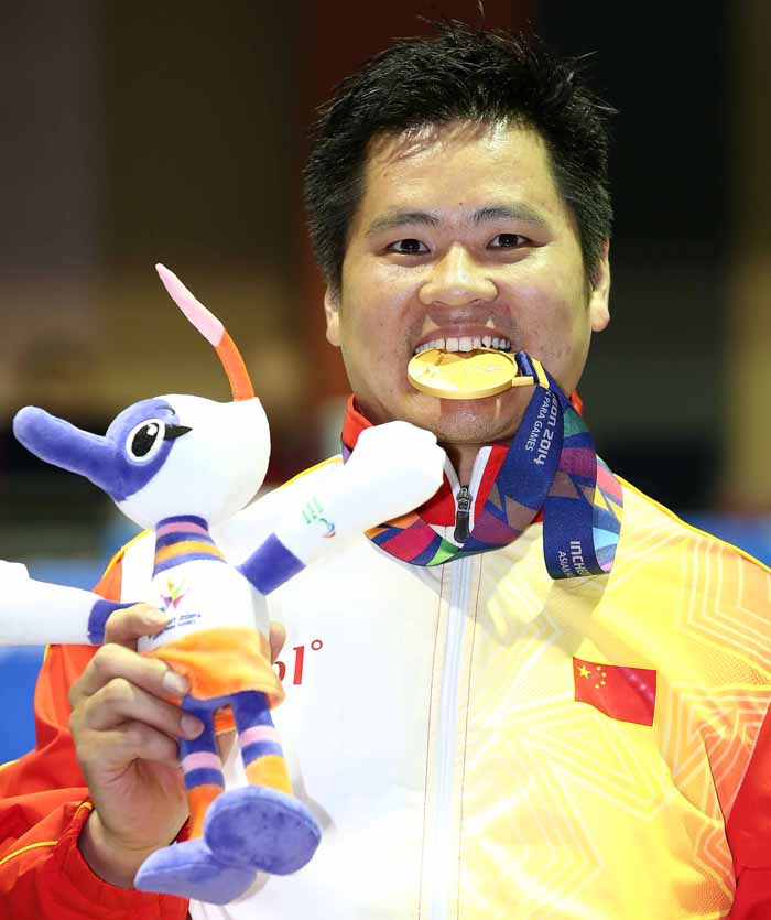  Hu Daoliang from China bites into his gold medal after winning the men's foil category B competition held in the Songdo Global University Gymnasium in Incheon on October 19. 