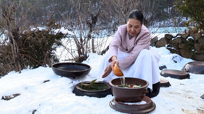 A woman collects her kimchi from large underground winter storage jars. (photo courtesy of the CHA)