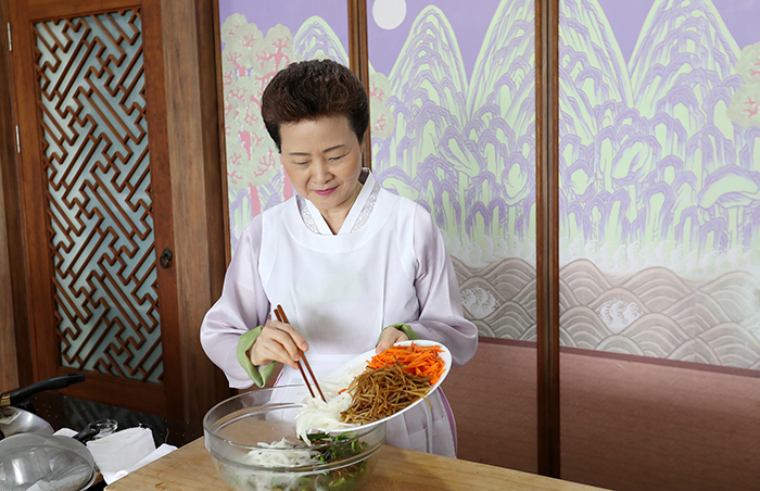 Director of the Institute of Traditional Korean Food Yoon Sook-ja mixes pre-prepared vegetables and glass noodles.
